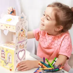 Uśmiechnięta dziewczynka ozdabia kartonowy domek, który jest świetną zabawka dla sześciolatków. Kolorowe kredki i farby czekają na użycie.