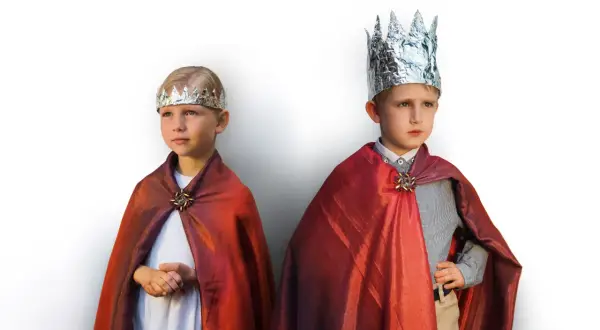 Dwóch chłopców w strojach świętych, z błyszczącymi koronami i czerwonymi płaszczami, gotowych na jasełka.