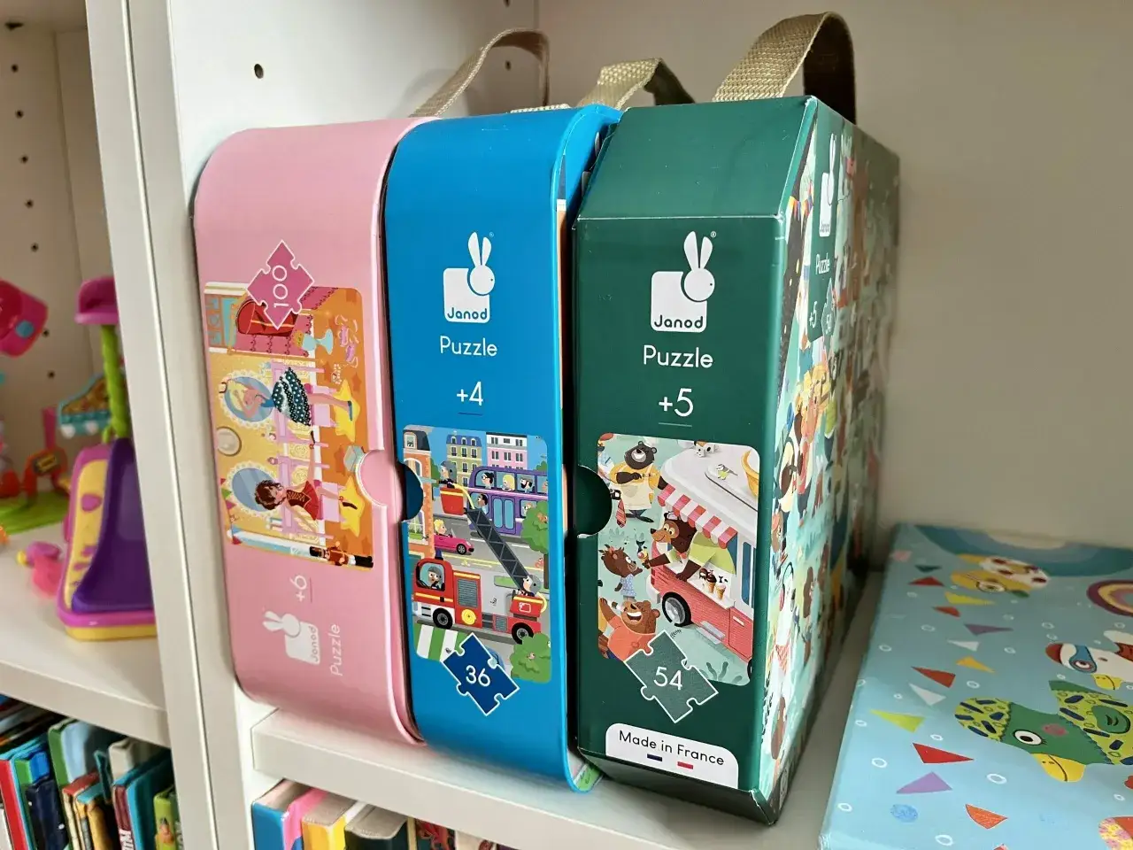 Trzy pudełka z puzzlami Janod: różowe (+6), niebieskie (+4) i zielone (+5). Idealne zabawki edukacyjne dla 4 latka i starszych.